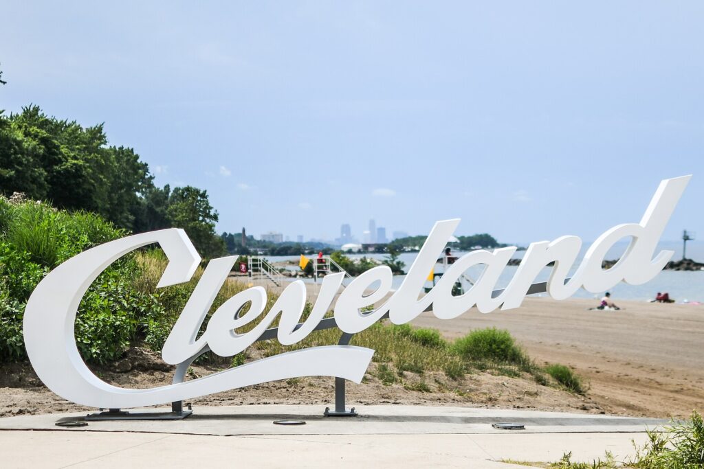 The script Cleveland sign at Euclid Beach Park on the Lake Erie shore, with the beach and the distant downtown skyline behind it