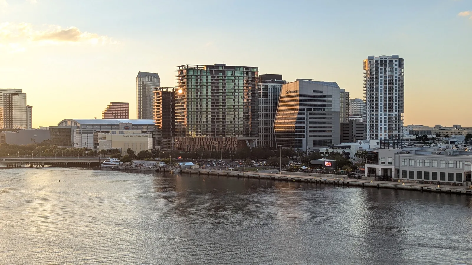 Downtown Tampa waterfront and glass towers glowing at sunset across calm water
