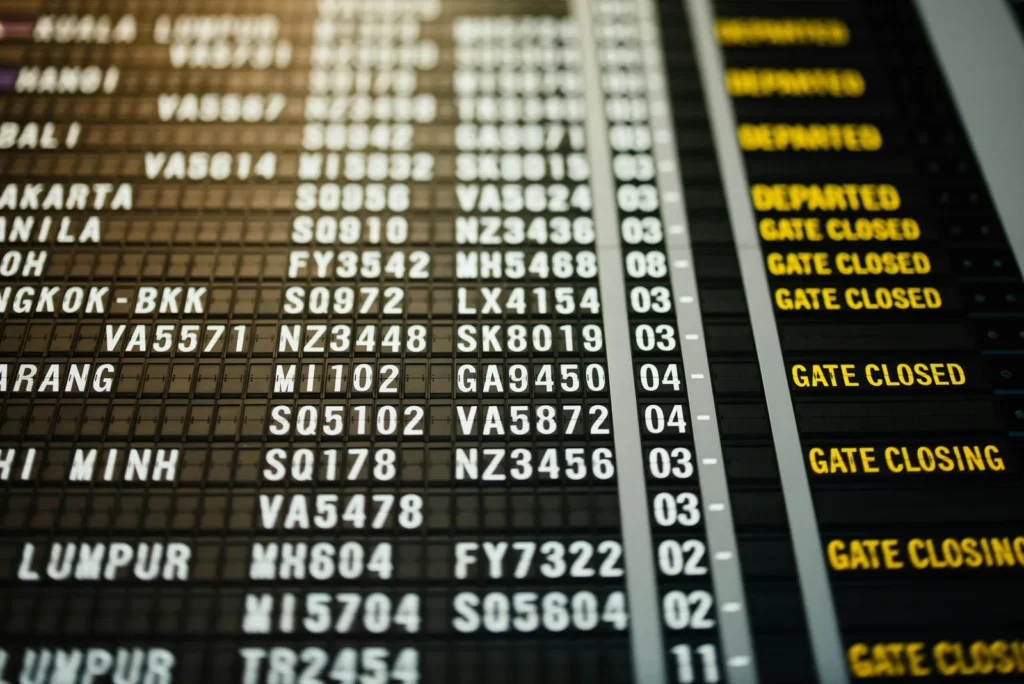 Close-up of an airport departures board listing flight numbers and destinations such as Manila, Bangkok and Kuala Lumpur, with several flights marked Departed, Gate Closed or Gate Closing.