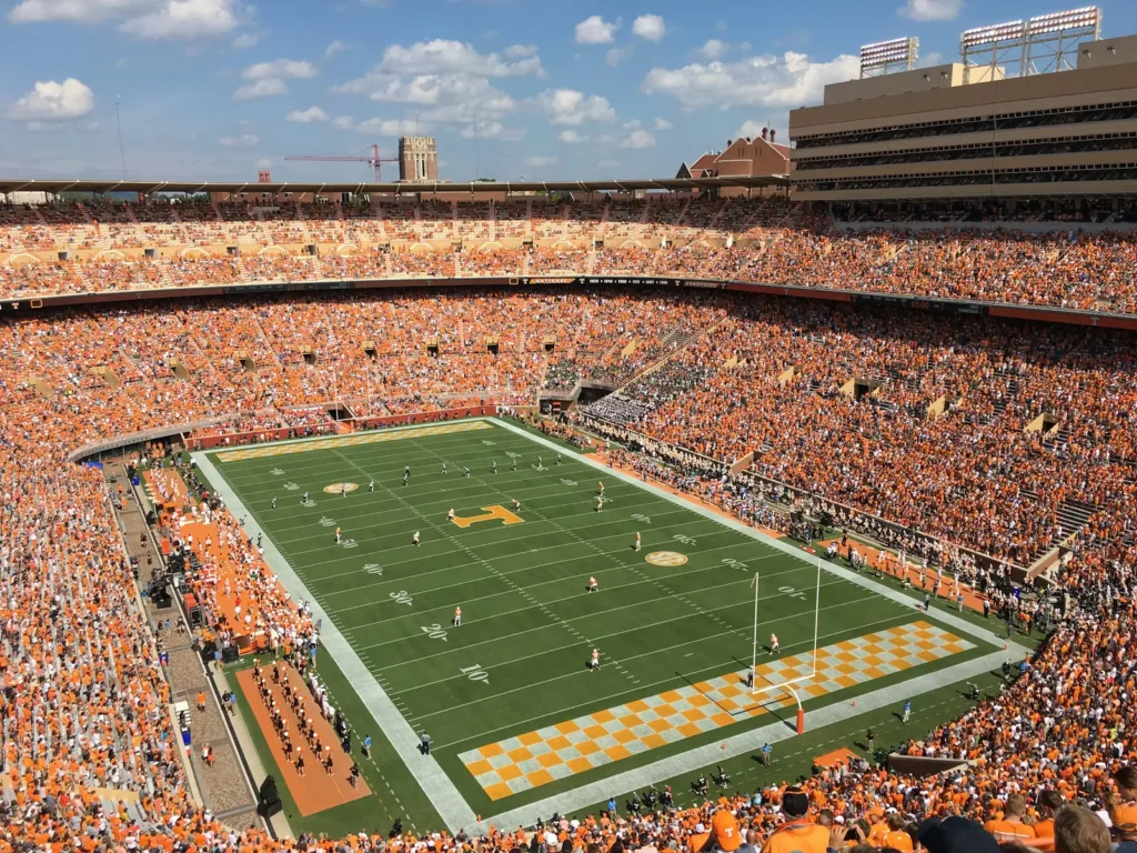 A packed Neyland Stadium seen from the upper deck, with fans in orange filling the stands around a field with orange-and-white checkerboard end zones