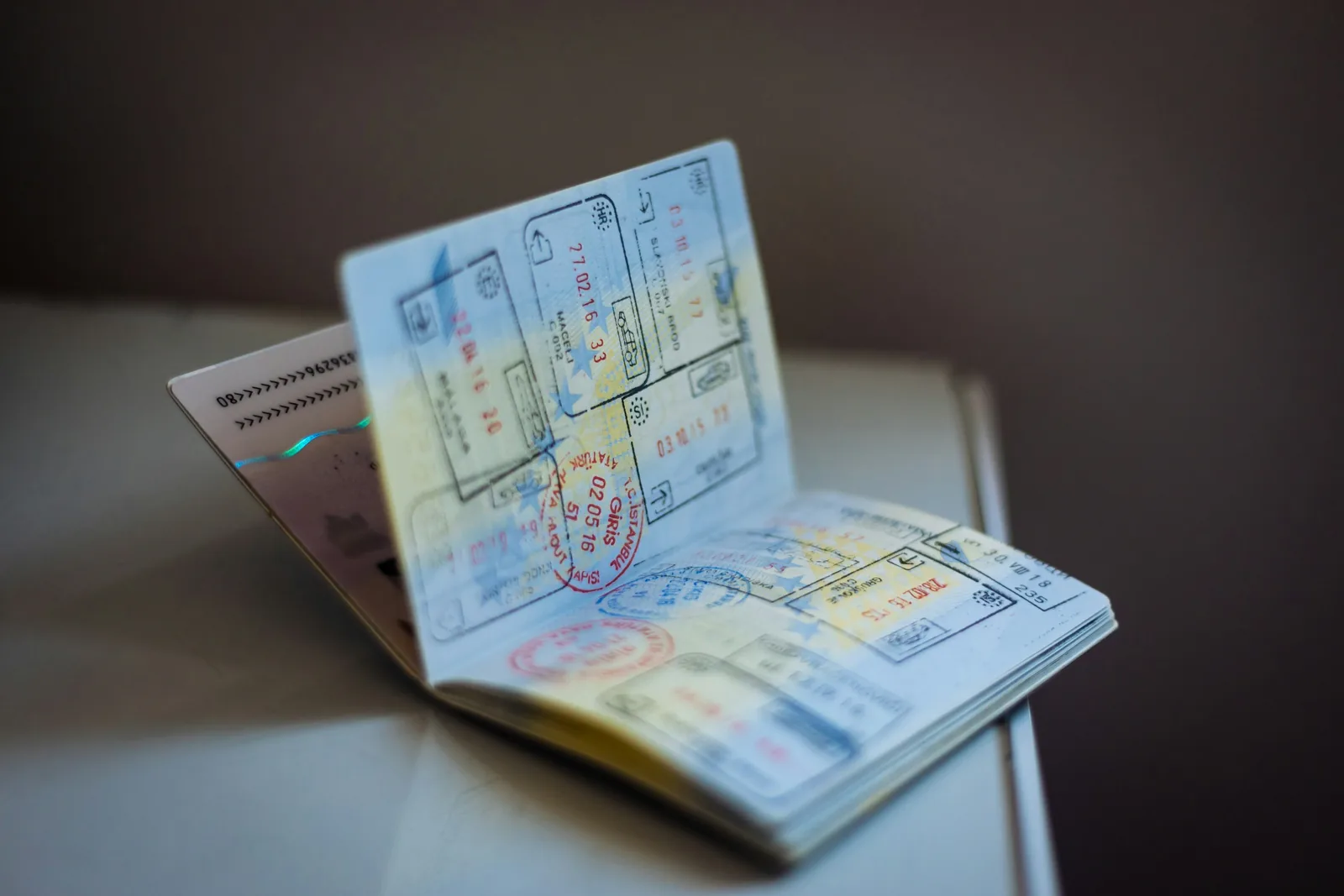 An open passport lying on a table, its pages covered with dozens of colorful ink travel stamps