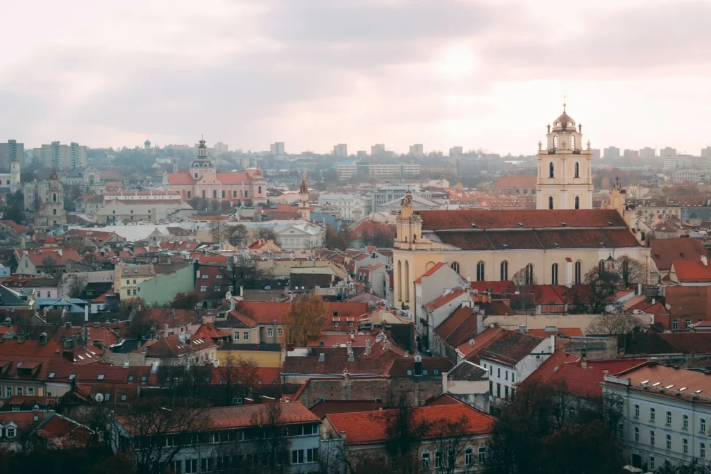 Red-tiled rooftops and a church tower in the old town of Vilnius, Lithuania, under an overcast autumn sky