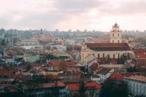 Red-tiled rooftops and a church tower in the old town of Vilnius, Lithuania, under an overcast autumn sky
